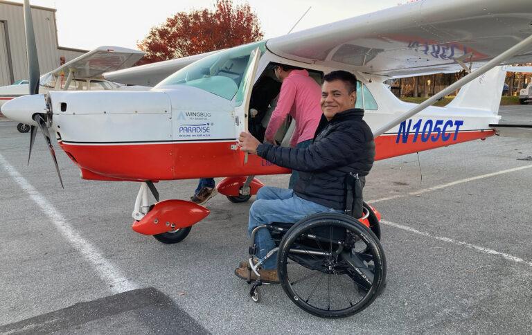 Ahuja sitting in wheelchair in front of plane