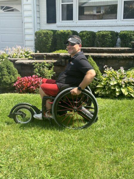Matt, a man in a wheelchair, smiles in his garden while using his free wheel and smart drive