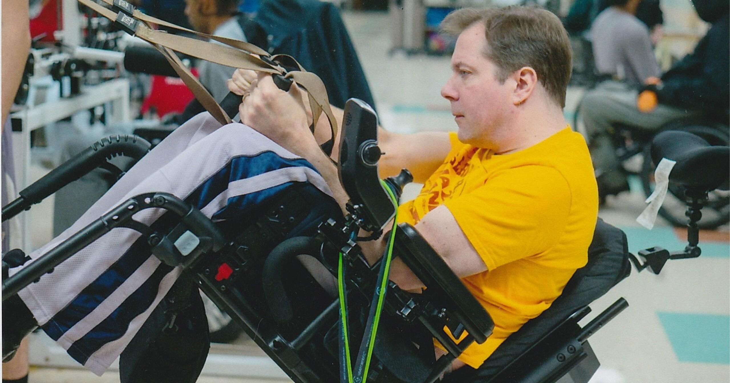 A wheelchair user in a yellow shirt hangs onto the reins of an unseen horse.