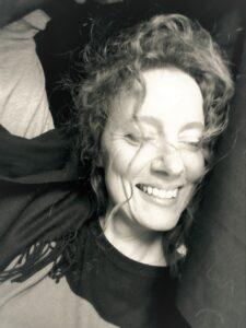 Laurie Crosby, a white woman with curly hair, smiles in a close up black and white photo.