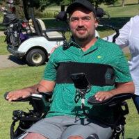 Wheelchair user in a green shirt sitting in his power chair on a nice sunny day. 