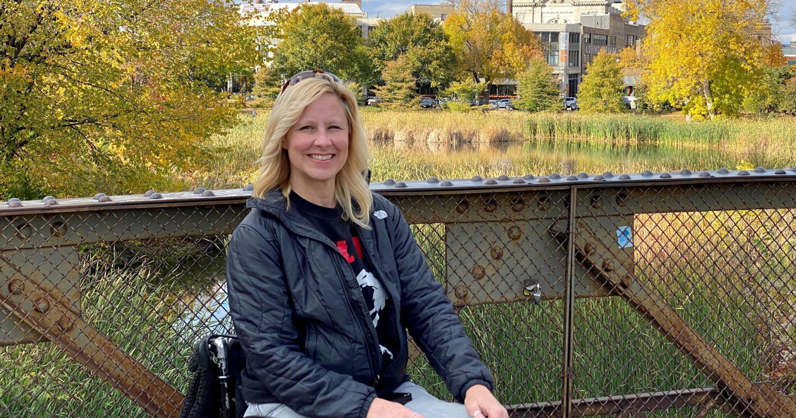 Char Vine sits in her wheelchair in front of a scenic view.