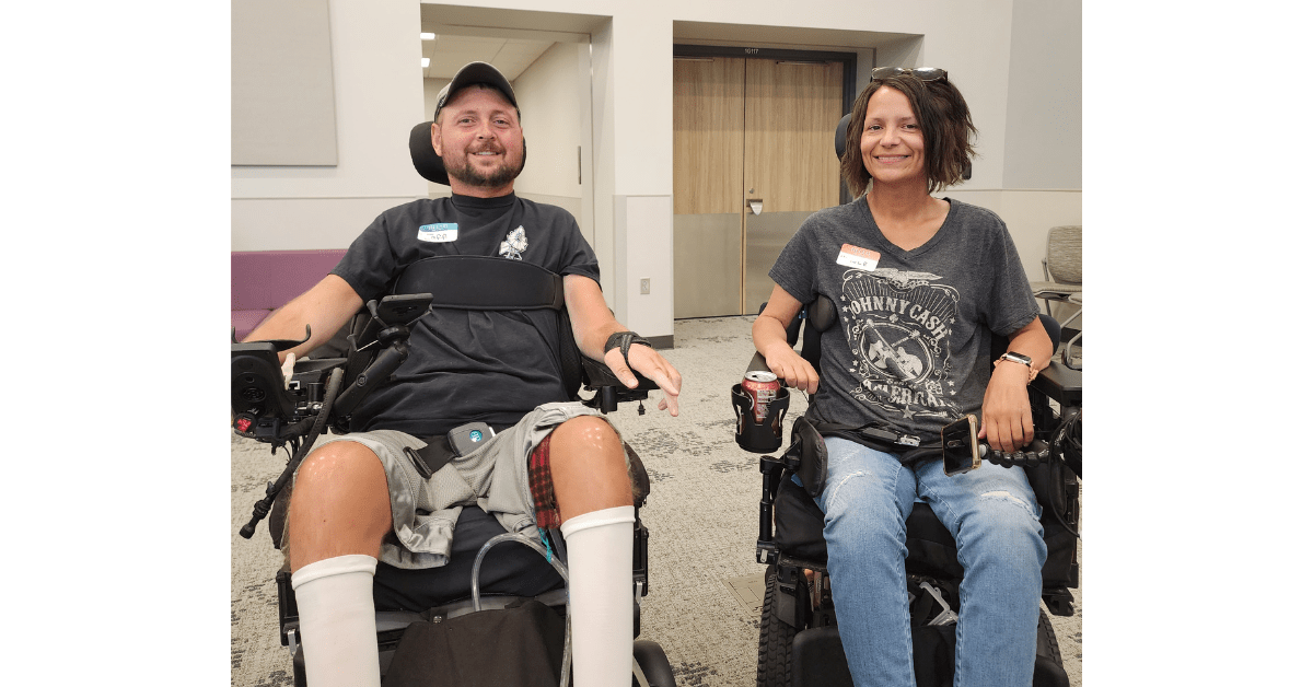 two wheelchair users smile at the camera