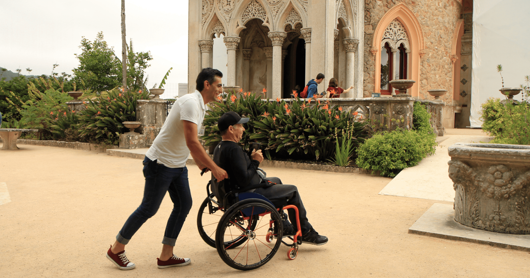 an older man in a wheelchair is being pushed by his caregiver.