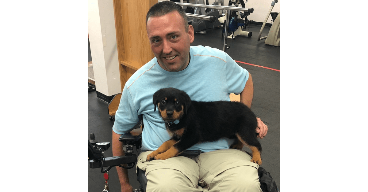 kevin mullins is a white man in a powerchair, he is sitting with his dog on his lap