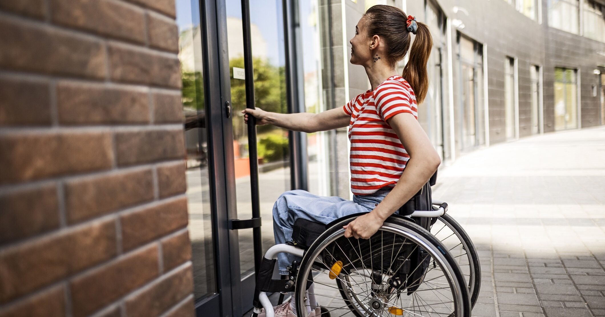 Woman in wheelchair entering the building opening doors