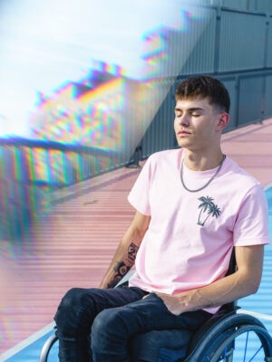 vertical cropped portrait of young male with tattoos and physical disability on pink clothes. Social inclusion lifestyle.