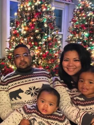 lesly st. louis, a black man and wheelchair user, sits in front of a christmas tree with his family.