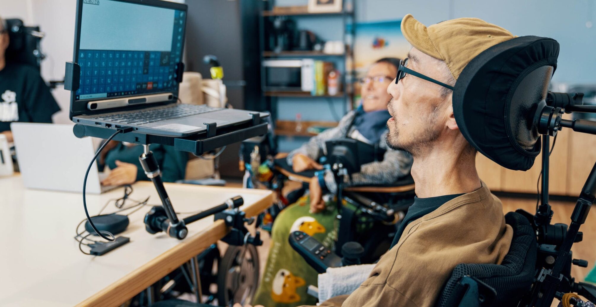 Two wheelchair users working on a computer screen together