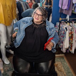 woman in denim jacket and leather pants sitting in powerchair in a clothing store