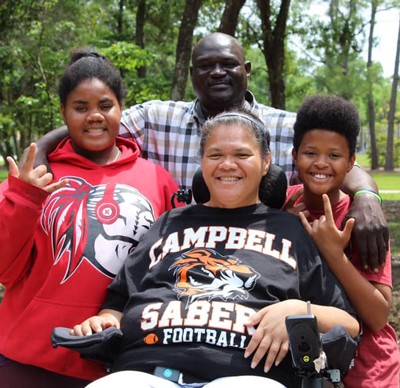 woman in powerchair surrounded by family in a park