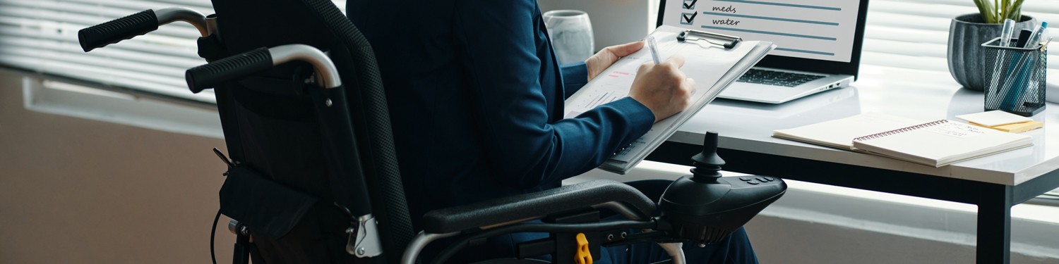 woman in power wheelchair sitting at desk
