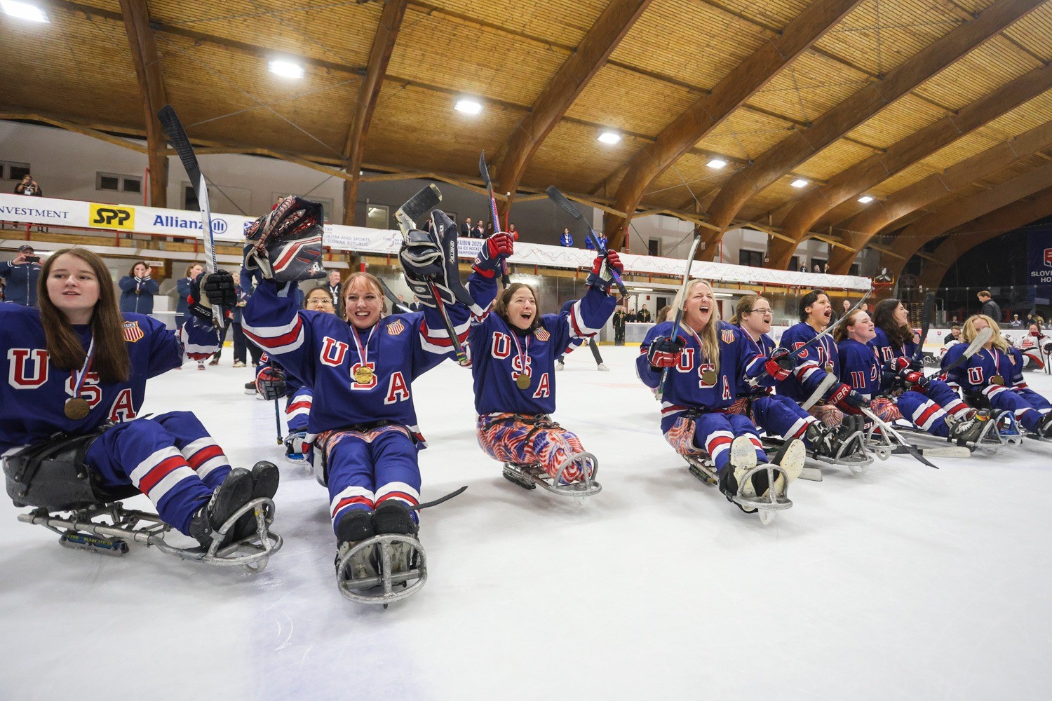 Team USA on the ice holding their sticks up in victory