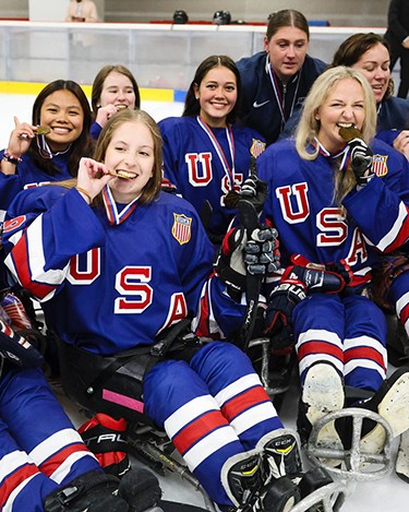 Team USA para hockey on the ice biting into their gold medals.