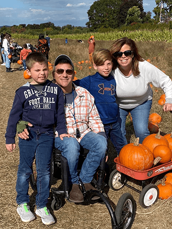 Family pictured in field with a wagon full of pumpkins.