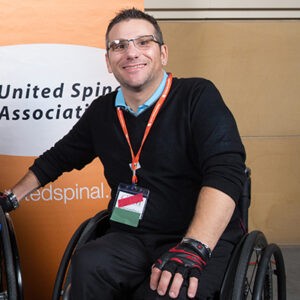 man in wheelchair in front of United Spinal banner