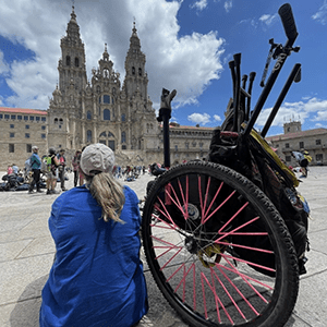 back of woman sitting on the ground with her wheelchair behind her and cathedral in the background