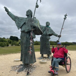 woman in wheelchair next to the sculptures Monumento al Peregrino